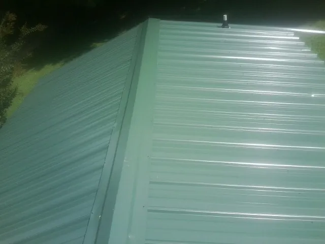 New green metal panels meeting at the ridge of a roof — Flat Roof Repair work by our crew in Casper