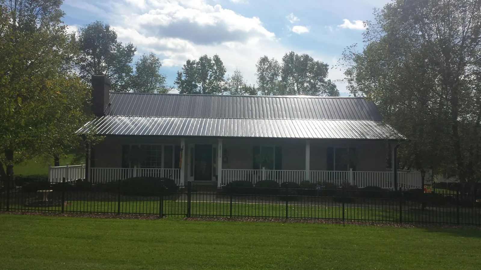 Gray metal roof on a brick ranch with a full width front porch — Gutter Guard Installation work by our crew in Casper