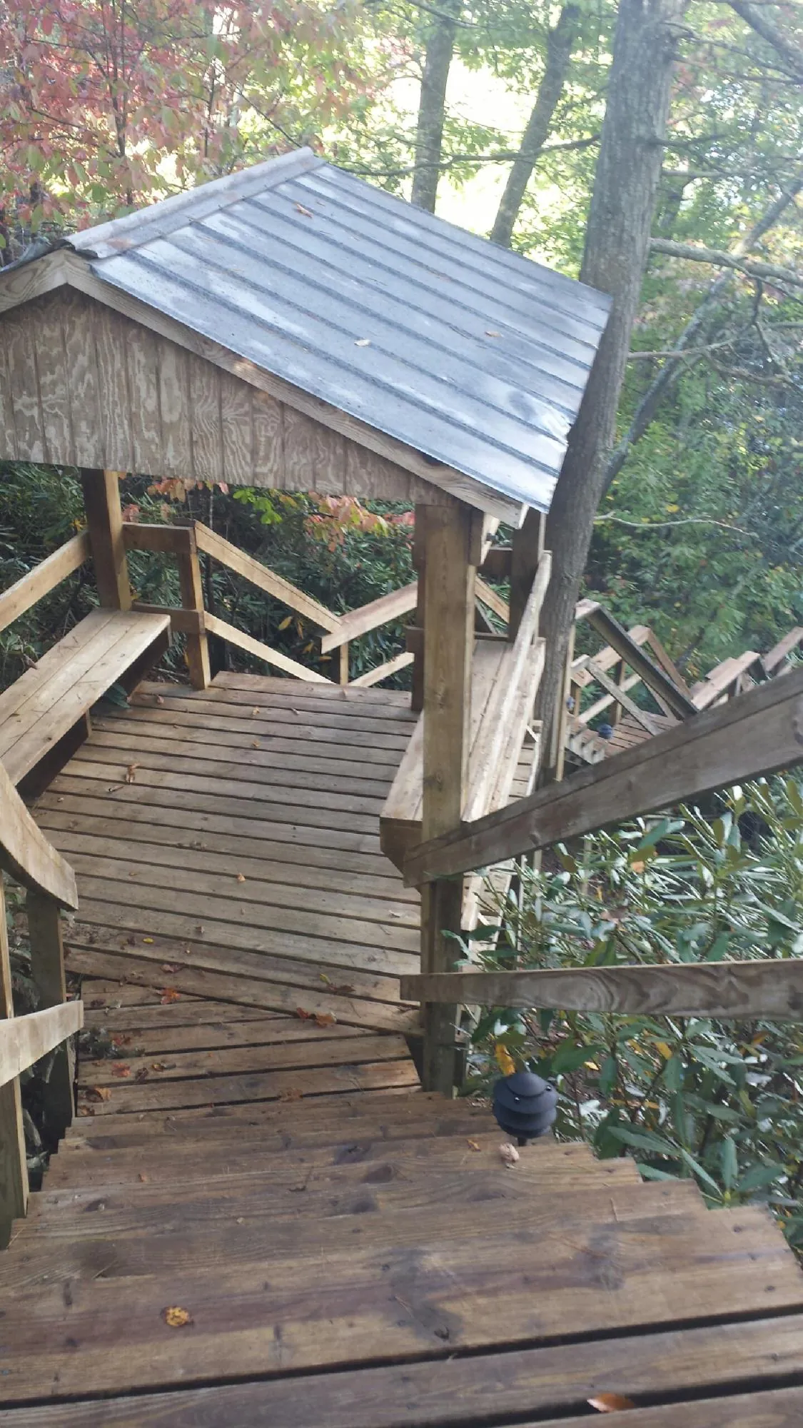 Metal roofed shelter over wooden steps on a wooded walkway — Skylight Repair & Installation work by our crew in Casper