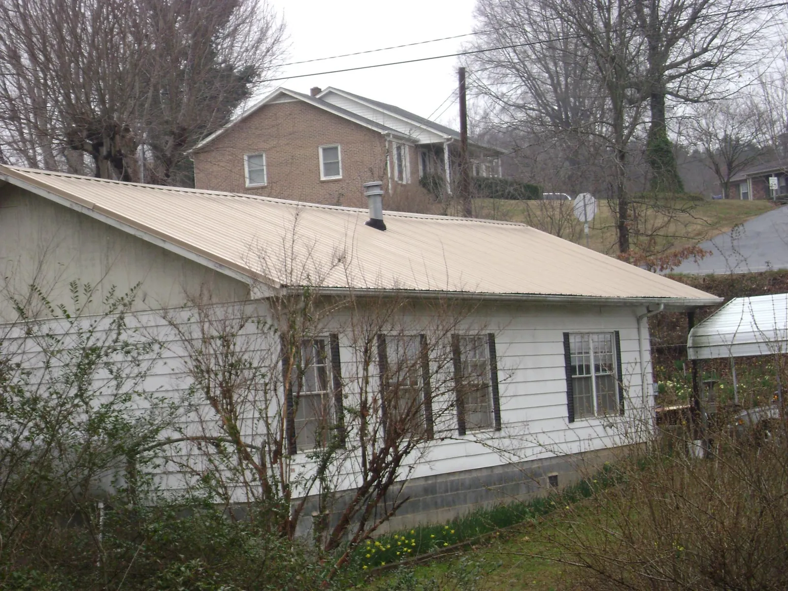 Tan metal roof on a white sided house set into a hillside — Commercial Roofing by Roofing Brothers in Casper