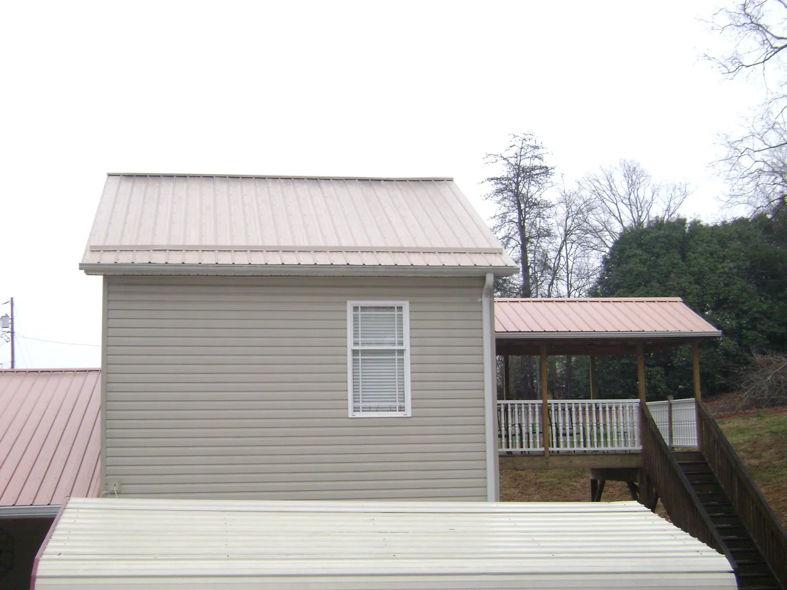 Tan metal roofs on a two story addition and attached porch, from a Roof Replacement job in Casper
