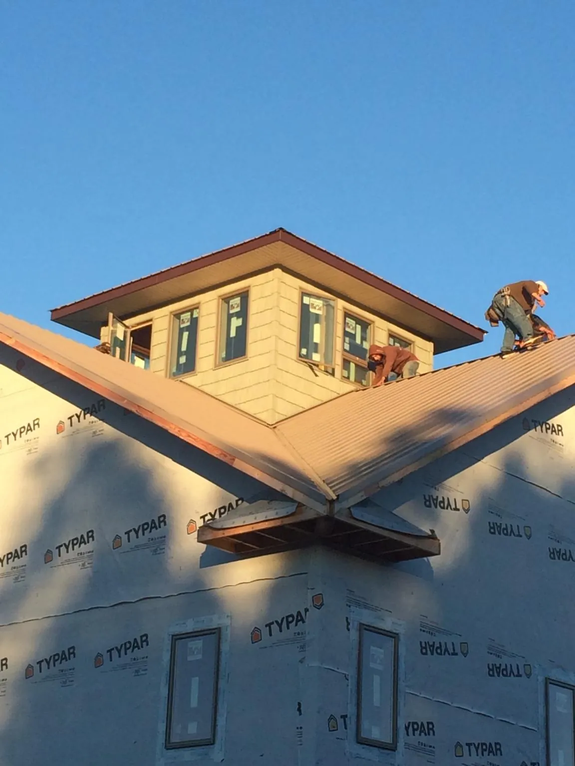 Roofers working around a rooftop cupola on a new metal roof at sunset — Roof Waterproofing in Casper by Roofing Brothers